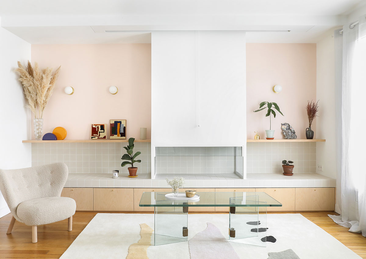 Salon minimaliste aux murs blancs et ivoire, tapis clair aux motifs pastels, et fauteuil beige